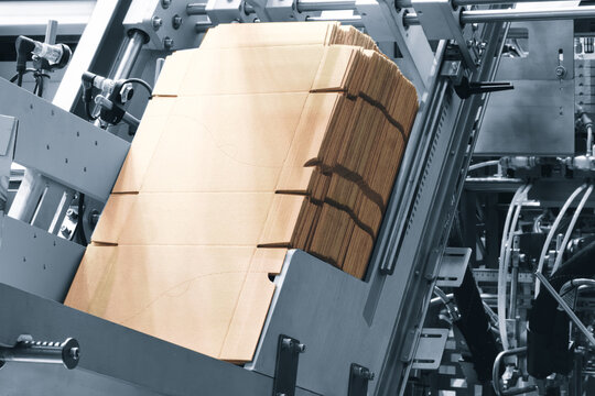 Elements of cardboard boxes are collected in stack. Conveyor line for the production of boxes. Machine cuts cardboard boxes from sheets of cardboard. Enterprise for  production package.