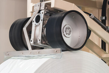 A machine with a roll of polyethylene plastic wrapping film on it. The machine is in a factory....
