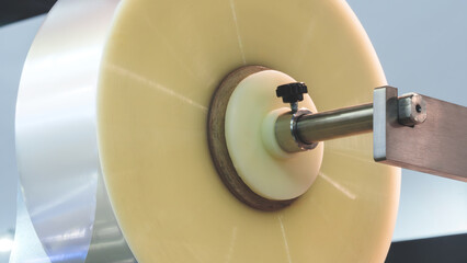 A machine with a roll of polyethylene plastic wrapping film on it. The machine is in a factory....