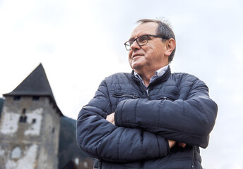 Elderly caucasian male in winter jacket by historic tower