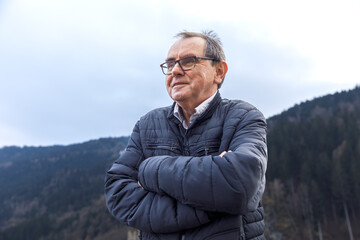 Elderly caucasian man in winter jacket enjoying mountain scenery