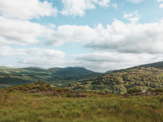 Majestic mountains dominate the horizon, their slopes covered in vibrant green vegetation. A...