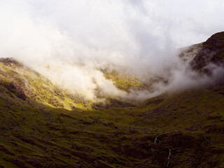Misty clouds drift through the valley of Carrauntoohill. Low-hanging clouds obscure the mountains...