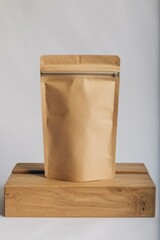A kraft paper pouch with a zipper seal sitting on a light wooden block against a white backdrop