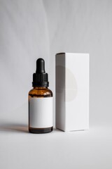 Amber dropper bottle with blank label and white box on a white surface in a studio setting