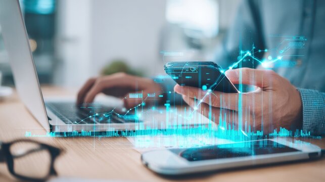 The business professional analyzing data on smartphone while using laptop.