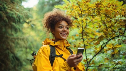 The joyful young woman enjoying nature while using her smartphone in the forest.