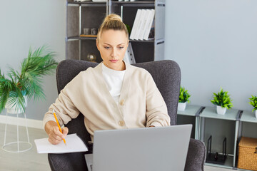 Photo of woman freelancer concentrated at laptop screen with serious expression, doing remote work,...