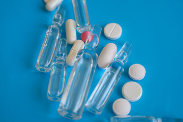 A striking close-up of medical ampoules and colorful pills, arranged on a rich blue background....