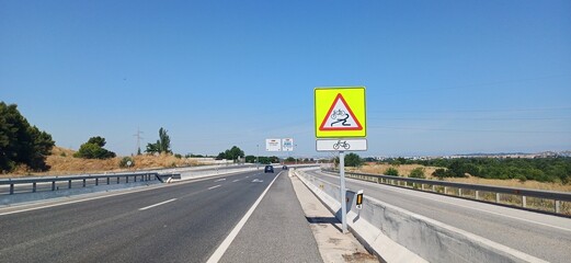 Warnschild „Achtung Rutschgefahr für Fahrradfahrer“ an Landstraße bei Madrid, Spanien
