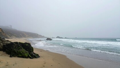 Fototapeta premium Foggy Beach Scene with Rocks and Gentle Waves on a Calm Day