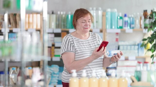 Mature female buyer scans code on package of ointment to check the expiration date. High quality 4k footage
