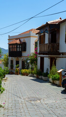 Mediterranean style houses with wooden balcony surrounded by green plants and bougainvillea in Kas, Turkey. Walking around city. Vertical image