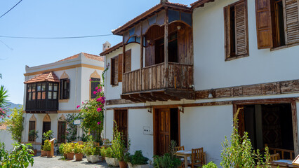 Mediterranean style houses with wooden balcony surrounded by green plants and bougainvillea in Kas, Turkey. Walking around city