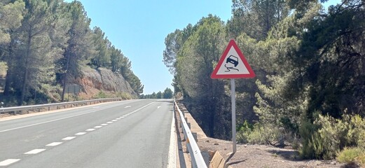 Warnschild „Achtung Rutschgefahr für PKW“ am Straßenrand in Spanien

