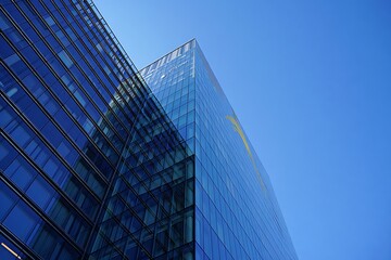 Modern glass office buildings reflecting clear blue sky and yellow abstract shape