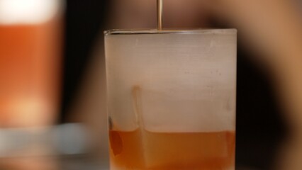 Closeup bartender pouring mixed cocktail whiskey into cool glass textured cooling ice drink making special advertisement creative focusing alcohol refresh showcase at VIP guest background. Vinosity.