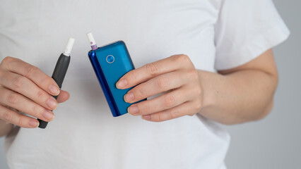 A woman compares two different tobacco heating systems. Electronic cigarette.