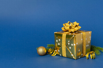 Golden gift box with christmas decor on color background