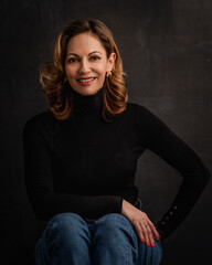 Studio shot of a blond haired woman smiling against dark background