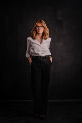 Studio shot of a blond haired woman smiling against dark background