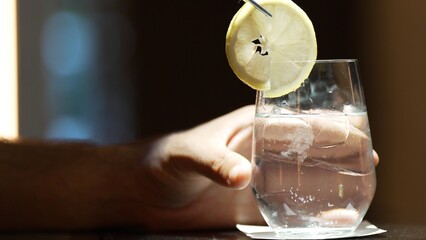Closeup bartender hand gin fizz or tonic garnished with slice lemonade serving luxury counter bar...
