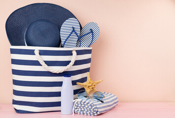 Blue beach bag with summer accessories on wooden table