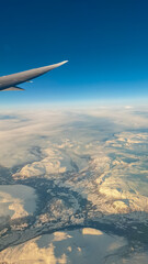 An awe-inspiring aerial view from an airplane window captures the tip of the wing soaring over a...