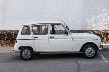 Classic white car next to a wall on a village street