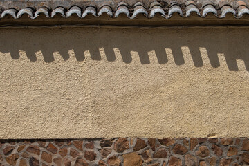 tiles casting their shadow on a yellow-painted plastered wall