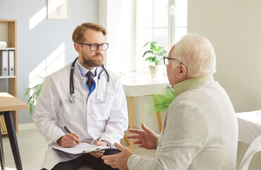 Doctor or nurse talking with senior man patient during medical consultation in hospital office,...