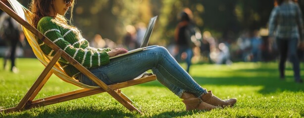 The woman enjoying a sunny day on the lawn while working on her laptop.