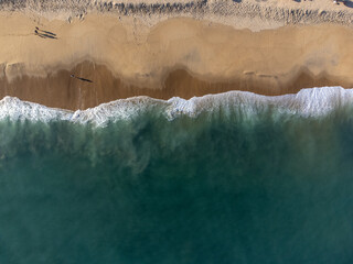 incredible view from above of the beach with blue water and waves forming
