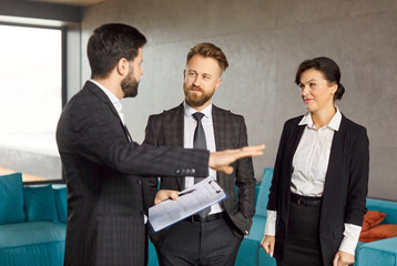 Confident realtor presenting commercial property to potential investors in office. Business...