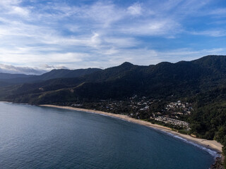 Setting sun on beautiful tropical beach amidst forested mountains