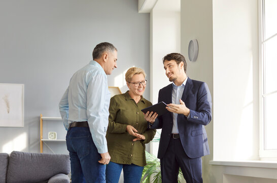Happy senior couple talking to real estate agent, clients consulting broker about house plan, project selling, buying new flat terms, investment, meeting discussing property plan, digital contract 