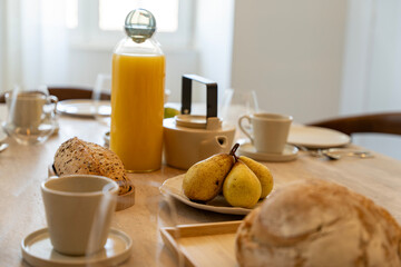 Petit déjeuner appétissant servi sur une élégante table en bois avec chaises en cannage, dans une salle lumineuse et chaleureuse.