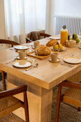 Petit déjeuner appétissant servi sur une élégante table en bois avec chaises en cannage, dans une salle lumineuse et chaleureuse.