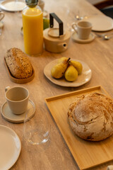 Petit déjeuner appétissant servi sur une élégante table en bois avec chaises en cannage, dans une salle lumineuse et chaleureuse.