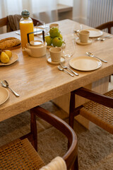 Petit déjeuner appétissant servi sur une élégante table en bois avec chaises en cannage, dans une salle lumineuse et chaleureuse.