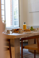 Petit déjeuner appétissant servi sur une élégante table en bois avec chaises en cannage, dans...