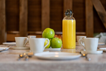 Petit déjeuner appétissant servi sur une élégante table en bois avec chaises en cannage, dans une salle lumineuse et chaleureuse. Zoom sur la composition de la table.