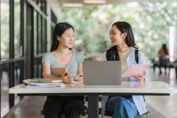 Obraz premium Two Asian Students Studying Together Outdoors