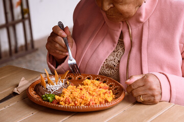 Elderly Mexican woman eating scrambled eggs