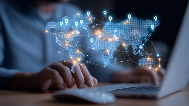 Global Connection: A person is working on a laptop with a holographic projection of the world map and location pins, illustrating the concept of global network, technology, and worldwide reach. 