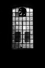 Dettaglio di una grande finestra all'interno di un capannone industriale con una ventola per l'aereazione