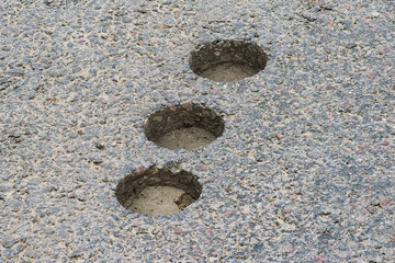 inspection round holes in asphalt left after checking the thickness and quality of the asphalt