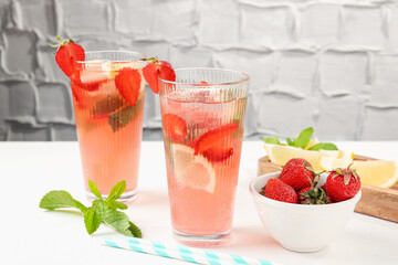 Refreshing drink with strawberries, mint and ice on white table against grey textured background, closeup