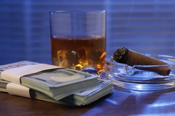 Mafia and criminal world. Money, ashtray with cigar and whiskey on wooden table, closeup
