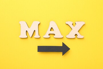 Word Max made of wooden letters and arrow on yellow background, flat lay